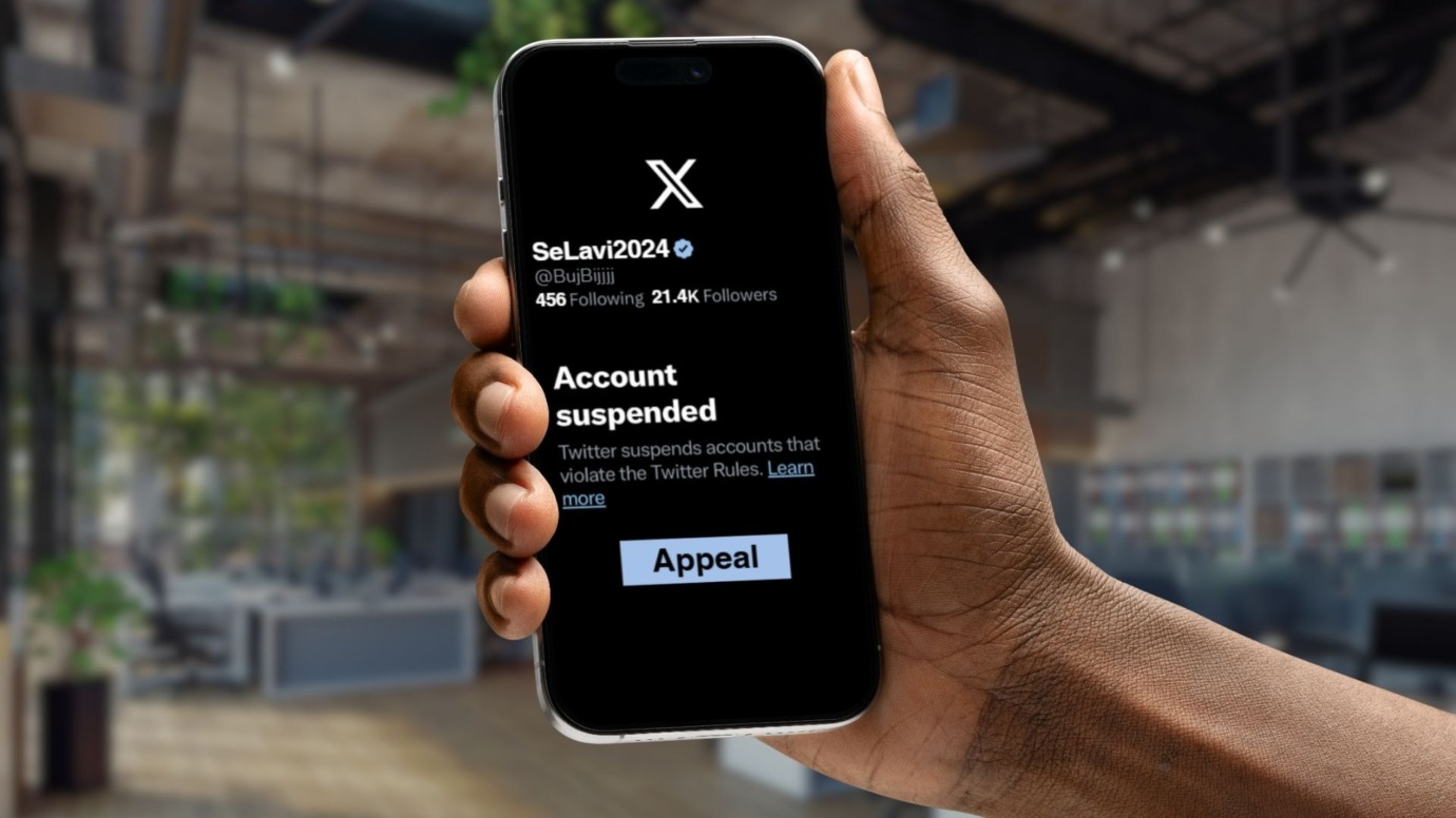 X account suspended hand holding phone with the notification
